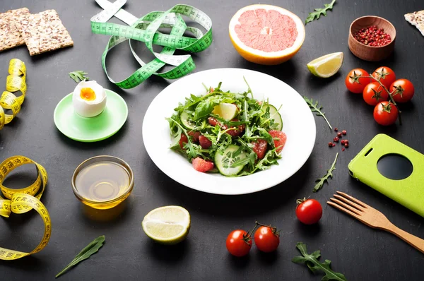 Conceptul de dietă. Salată cu arugula, felii de castraveți și un grapefruit pe o suprafață întunecată. O variație a dietei clasice cu grapefruit și ouă . — Fotografie, imagine de stoc