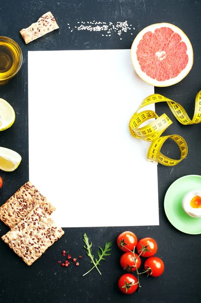 Обкладинка рецепту класичної дієти. Білий лист, навколо якого знаходяться продукти, включені в раціон дієтичної їжі, такі як грейпфрут, варене яйце, дієтичний хліб, помідори. Місце для запису тексту — стокове фото