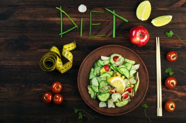 Konsept diyet gıda. Kelime diyet, soğan tüyleri kakma parçaları. Turp ve salatalık, yemek çubukları ve ölçüm bandı ile sonraki bahar salatası. Vegan kavramı.