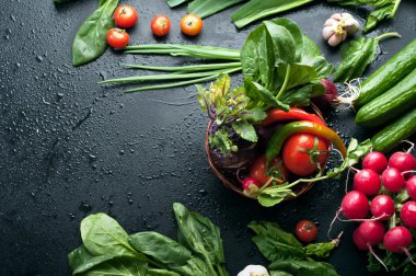 Siyah bir yüzeyde taze sulu sebze ve yeşillik. Metin yazmak için yer. Vegan kavramı. Kiraz, salatalık, ıspanak, yeşil soğan, lahana kohlrabi, redish ve diğer
