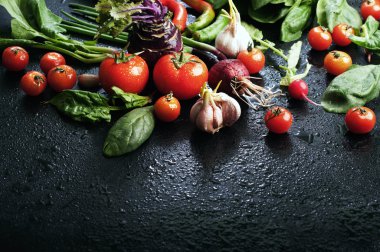 Siyah bir yüzeyde taze sulu sebze ve yeşillik. Metin yazmak için yer. Vegan kavramı. Kiraz, salatalık, ıspanak, yeşil soğan, lahana, kohlrabi
