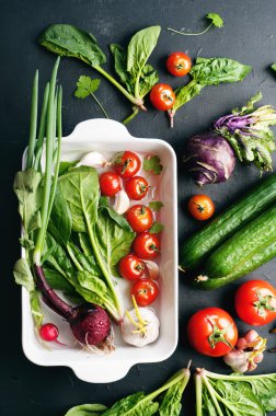 Siyah bir yüzeyde taze sulu sebze ve yeşillik. Vegan kavramı. Kiraz, salatalık, ıspanak, yeşil soğan ve lahana kohlrabi