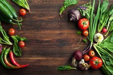 Taze sulu sebze ve otlar, turp gibi, soğan, ıspanak, domates ve acı biber kahverengi bir ahşap tahta üzerinde. Vegan kavramı. Sebze arka planı. Metin için alan