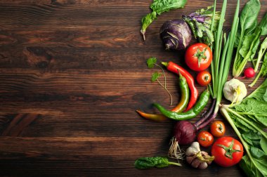 Taze sulu sebze ve otlar, turp gibi, soğan, ıspanak, domates ve acı biber kahverengi bir ahşap tahta üzerinde. Vegan kavramı. Sebze arka planı. Metin için alan