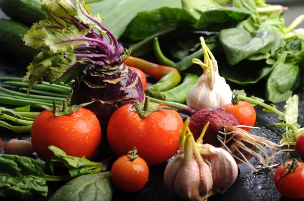 Verduras y verduras frescas y jugosas, como cebollas, tomates, espinacas, ajo, col, colinabo, en una superficie negra. Fondo vegetal. Concepto vegano —  Fotos de Stock