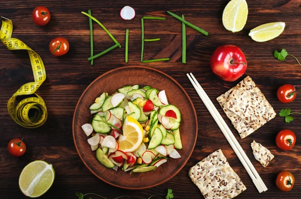 Koncept diet Food. Ordet diet, inläggningar bitar av lök fjädrar. Nästa vår sallad med rädisor och gurkor, pinnar och måttband. Vegan Concept. — Stockfoto