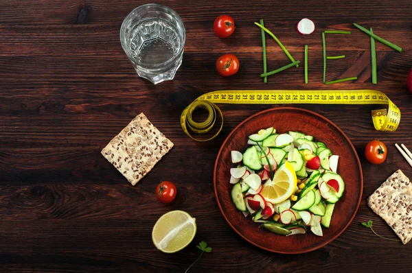 Concept diet food. Seasonal salad of radish and cucumber, next to which is a dietary bread, chopsticks, apples, tomatoes, a glass of water. Vegan concept. East style — Stock Photo, Image