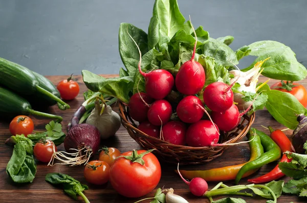 Verse sappige groenten en kruiden, zoals radijsjes, spinazie, tomaten en hete pepers op een bruin houten bord. Vegan concept. Plantaardige achtergrond. Ruimte voor tekst — Stockfoto