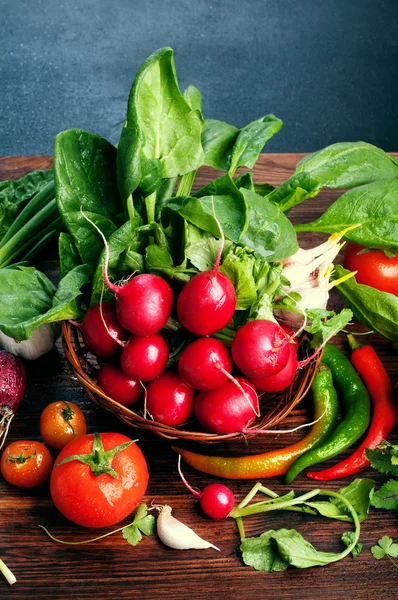 Légumes et herbes fraîches juteuses, comme les radis, les épinards, les tomates et les piments forts sur une planche de bois brun. Concept végétalien. Fond de légumes. Espace pour le texte — Photo