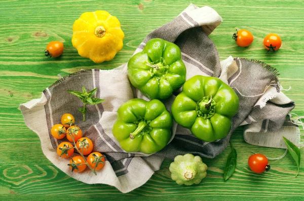 Frische saftige grüne Paprika, Kürbis und gelbe Tomaten auf grünem Hintergrund. Farm Food Konzept. Gemüse über (Hintergrund)) — Stockfoto