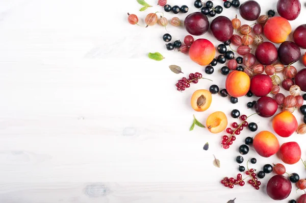 Fondo de bayas de verano (fondo de pantalla). Dispersión de frutas y bayas frescas maduras, como grosellas, cerezas, grosellas rojas y negras, melocotones y ciruelas sobre un fondo blanco. Lugar para escribir texto. Concepto vegano —  Fotos de Stock