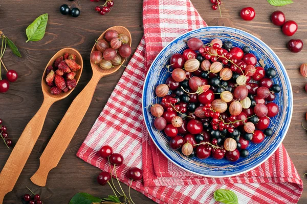 Prato azul com bagas suculentas frescas, como cerejas, groselhas, morangos, groselhas pretas e vermelhas. Comida de dieta de conceito. Fundo de baga de verão (papel de parede ) — Fotografia de Stock