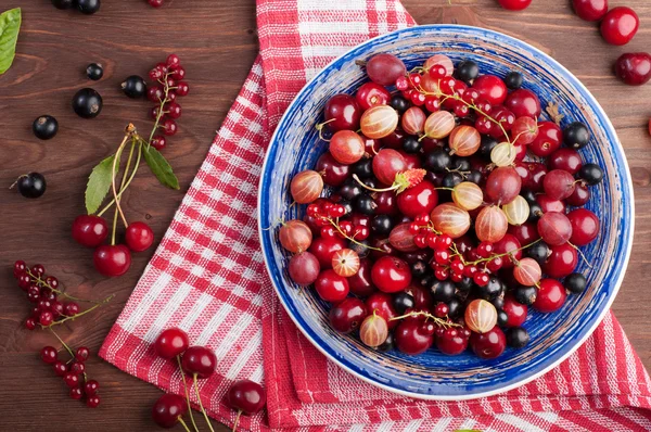 Prato azul com bagas suculentas frescas, como cerejas, groselhas, morangos, groselhas pretas e vermelhas. Comida de dieta de conceito. Fundo de baga de verão (papel de parede ) — Fotografia de Stock