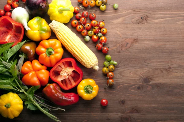 Concept d'alimentation biologique. Légumes frais juteux tels que tomates cerises, poivrons colorés et maïs sur un fond en bois brun. Produits végétariens et végétaliens. Espace pour le texte — Photo