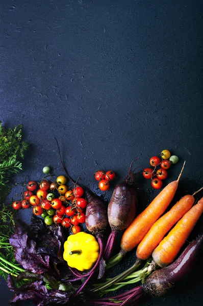 stock image Organic food concept. Fresh juicy vegetables such as carrots, beets, squash and colorful cherry on a dark surface. Vegetarian, vegan products. Space for text