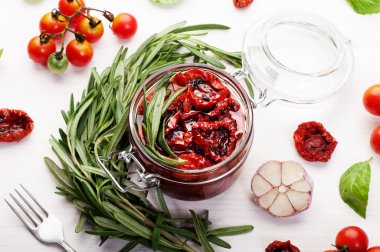 Beyaz bir arka plan üzerinde cam bir kavanozda güneşte kurutulmuş domates. Vejetaryen, vegan konsepti. Akdeniz ve İtalyan mutfağı