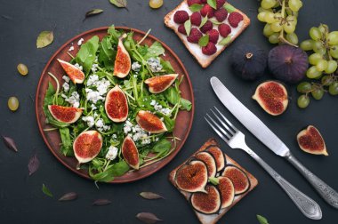 Arugula, incir ve mavi peynir ile hafif yaz salatası. Yumuşak peynir ve incir, yeşil üzüm ve fesleğen yaprakları gibi çeşitli topingler ile meyve sandviç yakın. Düşük kalorili besleyici hazır yemek. Sonbahar menüsü