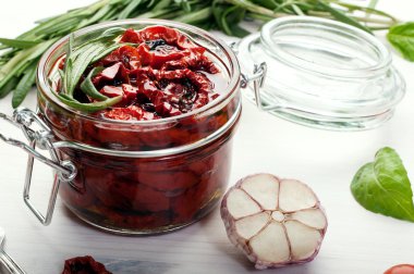 Beyaz bir arka plan üzerinde cam bir kavanozda güneşte kurutulmuş domates. Vejetaryen, vegan konsepti. Akdeniz ve İtalyan mutfağı