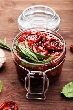 Kahverengi ahşap arka plan üzerinde cam bir kavanozda güneşte kurutulmuş domates. Vejetaryen, vegan konsepti. Akdeniz ve İtalyan mutfağı