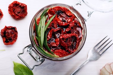 Beyaz bir arka plan üzerinde cam bir kavanozda güneşte kurutulmuş domates. Vejetaryen, vegan konsepti. Akdeniz ve İtalyan mutfağı