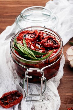 Kahverengi ahşap arka plan üzerinde cam bir kavanozda güneşte kurutulmuş domates. Vejetaryen, vegan konsepti. Akdeniz ve İtalyan mutfağı