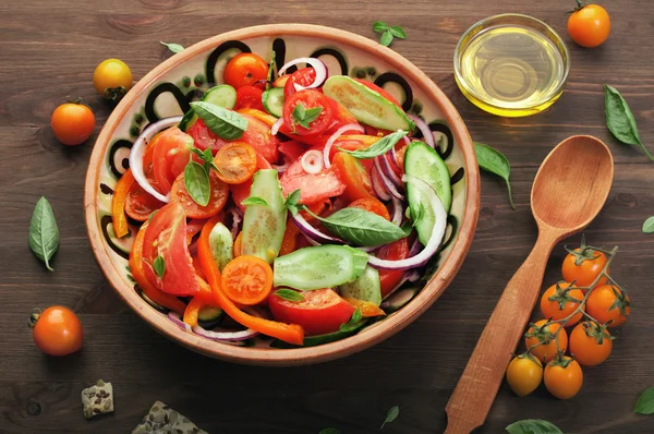 Salade d'été végétalienne diététique à la tomate rouge, au concombre, à l'oignon violet et aux feuilles de basilic sur fond de bois brun. Concept végétalien. Alimentation diététique. Repas cuisiné faible en calories — Photo