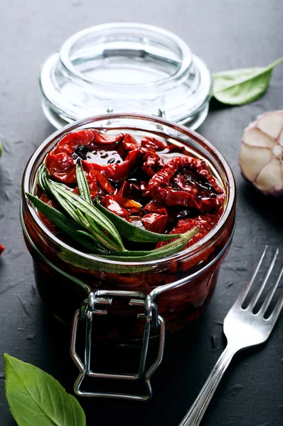 Tomates secados al sol en un frasco de vidrio sobre un fondo oscuro. Vegetariano, concepto vegano. Cocina mediterránea e italiana — Foto de Stock