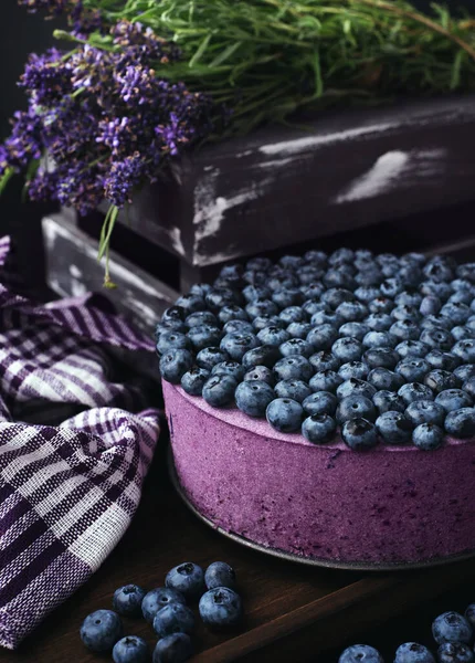 Kahverengi tahtada yaban mersinli krem peynirli pasta, lavanta çiçeklerinin yanında.