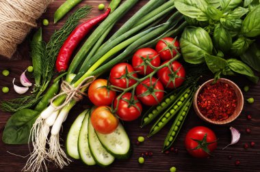 Vegetarian concept with fresh vegetables on wooden board. Tomatoes, chives, basil, young peas and chili peppers on a wooden board.