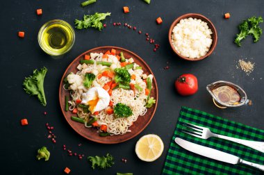 Kahverengi kil bir tabak kızarmış sebze ile yumurta noodles. Baharat ve otlar yanında. Koyu arka plan, arka aydınlatma.
