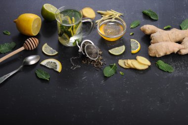 Çay nane, limon, limon ve zencefil karanlık bir arka plan üzerinde. Çay, kıyılmış zencefil kökü gibi için malzemeler yanında nane yaprakları, dilim limon ve kireç. İlaç ve ilaç kullanmaya gerek kalmadan soğuk algınlığı tedavisinde kavramı