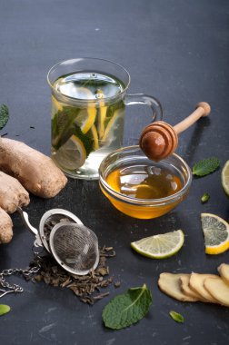Çay nane, limon, limon ve zencefil karanlık bir arka plan üzerinde. Çay, kıyılmış zencefil kökü gibi için malzemeler yanında nane yaprakları, dilim limon ve kireç. İlaç ve ilaç kullanmaya gerek kalmadan soğuk algınlığı tedavisinde kavramı