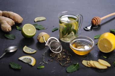 Çay nane, limon, limon ve zencefil karanlık bir arka plan üzerinde. Çay, kıyılmış zencefil kökü gibi için malzemeler yanında nane yaprakları, dilim limon ve kireç. İlaç ve ilaç kullanmaya gerek kalmadan soğuk algınlığı tedavisinde kavramı