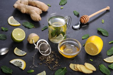 Çay nane, limon, limon ve zencefil karanlık bir arka plan üzerinde. Çay, kıyılmış zencefil kökü gibi için malzemeler yanında nane yaprakları, dilim limon ve kireç. İlaç ve ilaç kullanmaya gerek kalmadan soğuk algınlığı tedavisinde kavramı