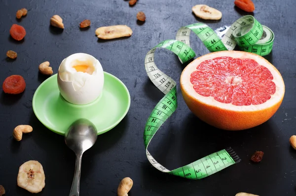 The concept of the classical diet with grapefruit and egg on a black background. — Stockfoto