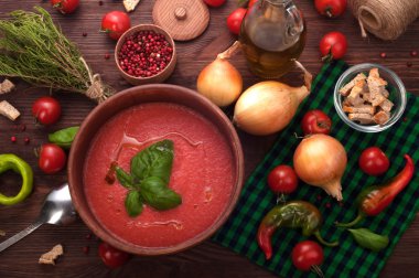 Cold soup gazpacho on a dark wooden background. Beside the ingredients for soup. Vegetarian concept