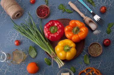 Vegetarian concept. Multi-colored pepper on a blue background, a number of spices and herbs.