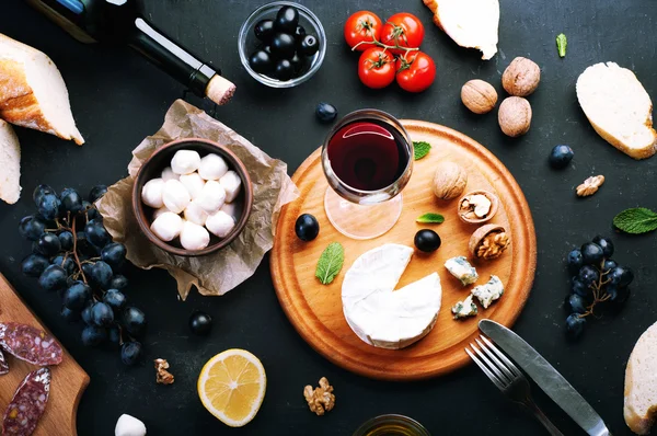 Italian food concept. Jerked sausage, various cheeses, blue grapes, vegetables and fruits on a dark background. — 스톡 사진