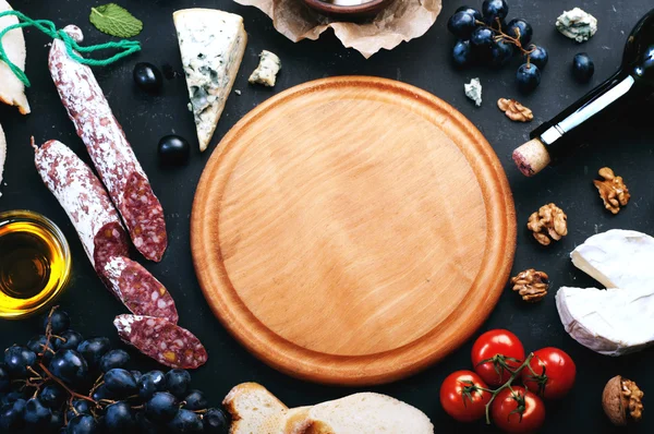 Round cutting board, next to which there are various products of the Italian cuisine. Place for writing text on a round cutting board. — 스톡 사진