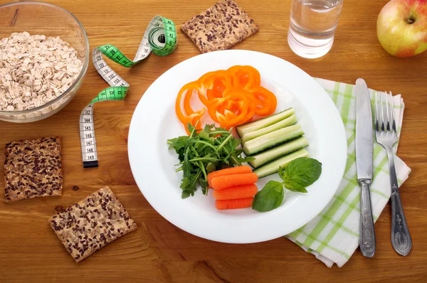 Comida de dieta de conceito. Café da manhã de arugula, cenouras jovens e pepino. Perto de aveia pão útil e um copo de água . — Fotografia de Stock