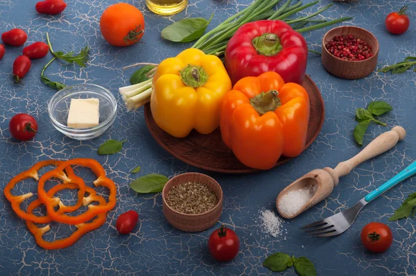 Vegetarian concept. Multi-colored pepper on a blue background, a number of spices and herbs. — Stockfoto
