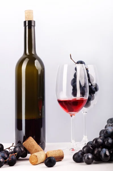 Концепция культуры потребления вина. Бутылка красного вина, бокал с красным бокалом вина с виноградом на белом фоне. Около винограда . — стоковое фото
