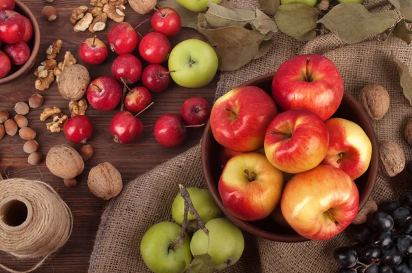 Νεκρή φύση με μήλα διαφορετικές ποικιλίες, σταφύλια και ξηρών καρπών σε σκούρο φόντο ξύλινη. Χορτοφάγους έννοια — Φωτογραφία Αρχείου