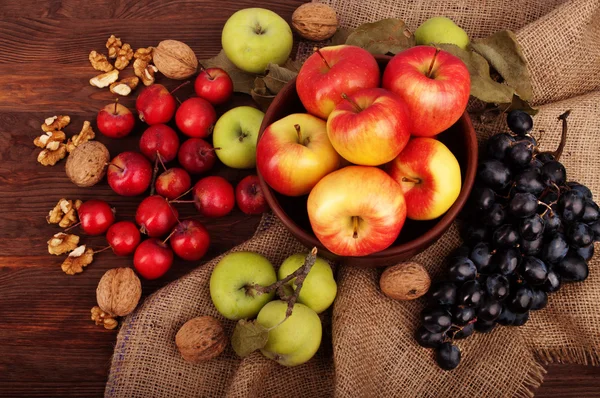 Natureza morta com maçãs de variedades diferentes, uvas e nozes em um contexto de madeira escuro. Conceito vegetariano — Fotografia de Stock