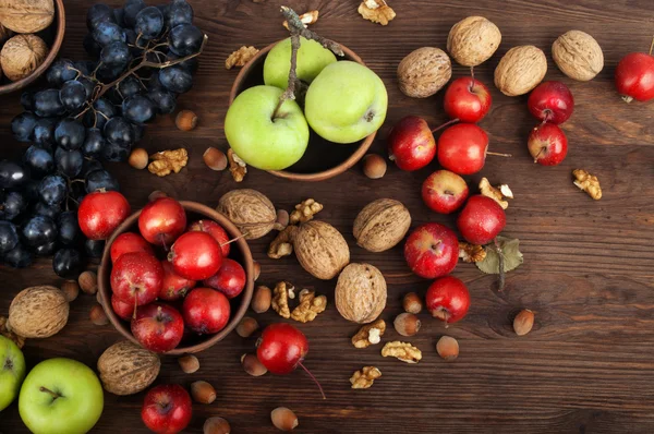 Zátiší s jablky různých odrůd, hrozny a ořechy na tmavém pozadí dřevěná. Vegetariánské pojetí — Stock fotografie