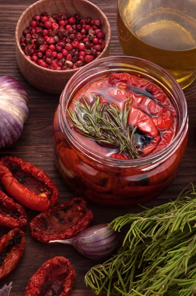 Tomates secados al sol en un frasco de vidrio, romero cerrado, aceite de oliva, ajo y especias. Cocina mediterránea — Foto de Stock