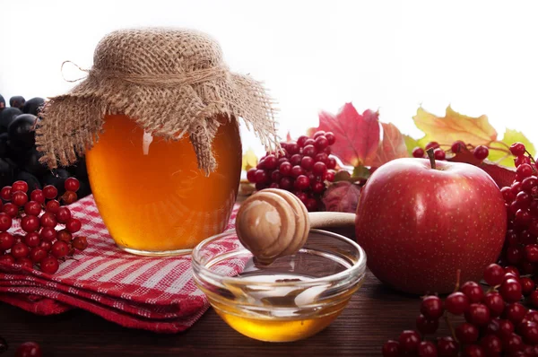Bodegón con miel, manzanas y hojas rojas sobre una tabla de madera. Fondo blanco. El concepto de productos útiles — Foto de Stock
