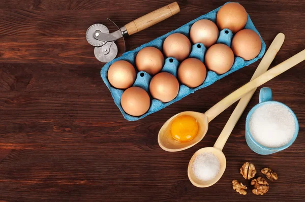 Ingredientes para cozinhar, como açúcar, ovos e farinha em um fundo de madeira escura. Antecedentes da receita . — Fotografia de Stock