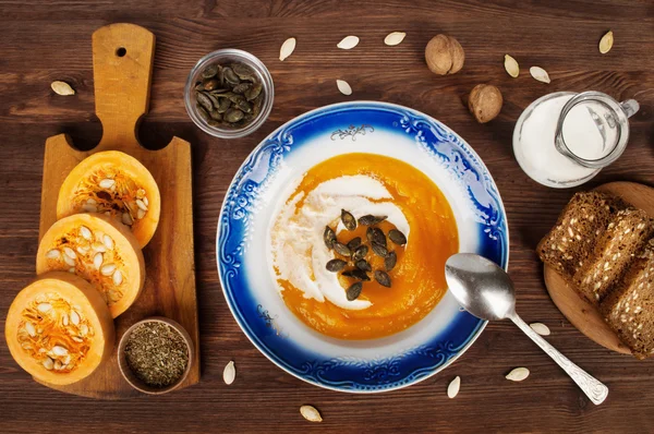Sütőtök krém leves, egy fából készült háttér, mellett a levest hozzávalókat. A koncepció a vegetáriánus menü — Stock Fotó