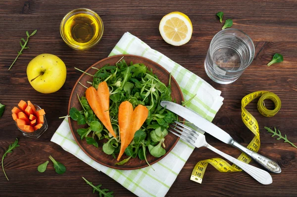 Concepto de dieta de alimentos. Ensalada con rúcula, puré de hojas y zanahorias sobre un fondo de madera oscura. Plato vegetariano saludable que promueve la pérdida de peso . —  Fotos de Stock